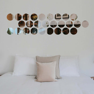 Decorative circular mirrors on a wall above a bed with neutral pillows.