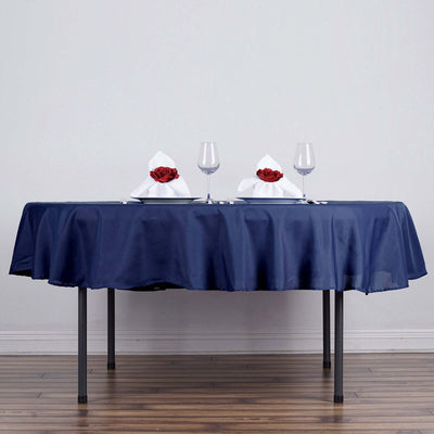 Elegant navy tablecloth set for a romantic dinner with glasses and rose-adorned napkins.