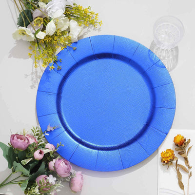 Blue decorative plate on a table with flowers and a clear cup.