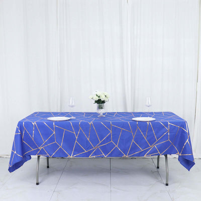 Blue geometric tablecloth on a dining table with plates and flowers.