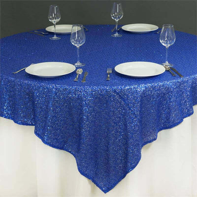 Round blue sequin tablecloth draped over a table set for dining.