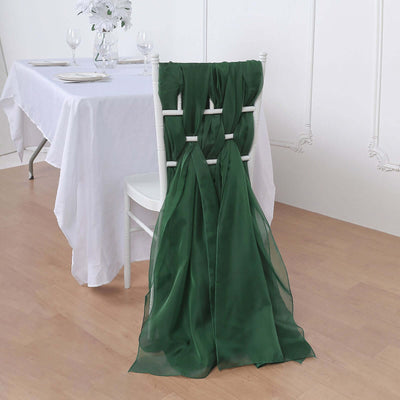 Green chiffon chair sash draped over a white chair at a dining table.