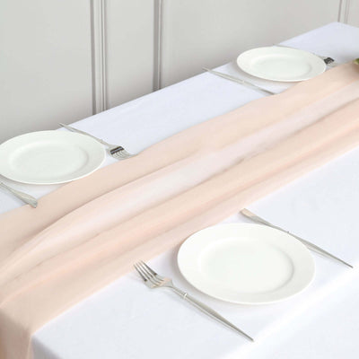 Elegant pink table runner on a white table setting with plates and cutlery.