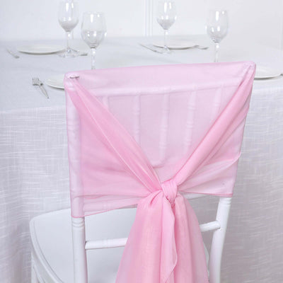 Pink chair sash tied on a white chiavari chair at an elegantly set table.