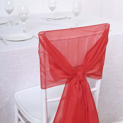 Red chair sash tied elegantly on a white chiavari chair at a dining table.