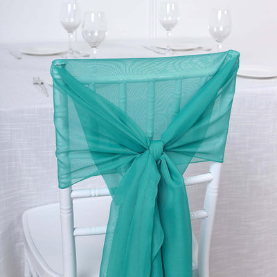 Turquoise chair sash tied elegantly on a white chair at a dining table.