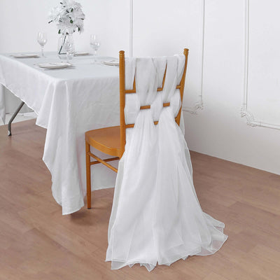 White chair with flowing sheer fabric draped over the back in a dining setting.