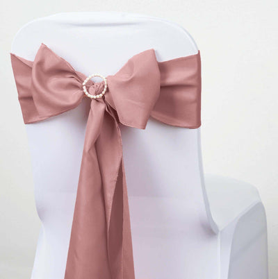 Blush satin chair sash with decorative ring on a white chair