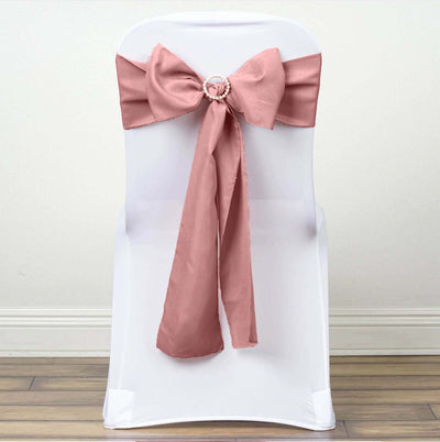 Pink satin chair sash with decorative buckle on white chair.