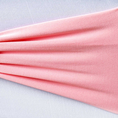 Soft pink fabric draped elegantly on a light surface.