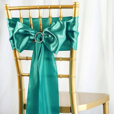 Teal satin chair sash with bow and rhinestone detail on a gold chair.