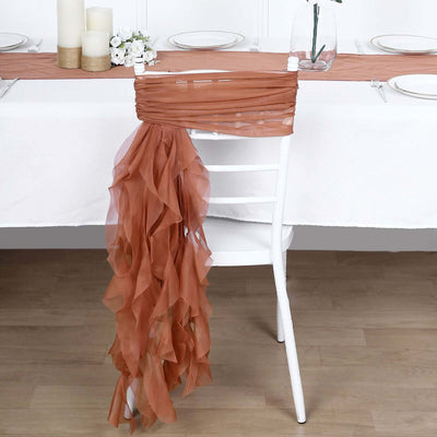 Rust-colored chiffon table runner draped over a white chair in a styled dining setup.