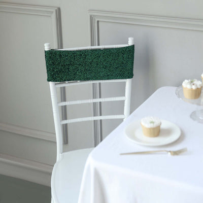 Green decorative chair back cover on a white chair in a styled dining setting.