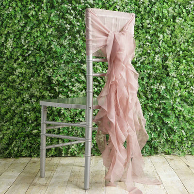 Silver chiavari chair with pink sheer ribbon bow against greenery backdrop.