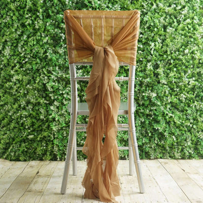 Elegant gold chair sash draped on a silver chiavari chair against a greenery backdrop.