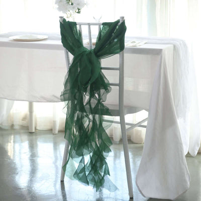 Green chiffon chair sash elegantly draped on a white chair in a bright setting.
