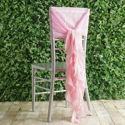 Pink chair sash tied in a bow on a silver chiavari chair against a greenery backdrop.