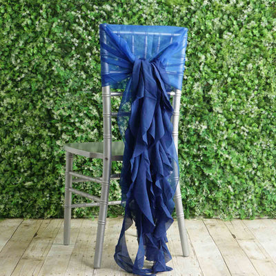 Navy blue chair sash tied on a silver chair against a greenery backdrop.