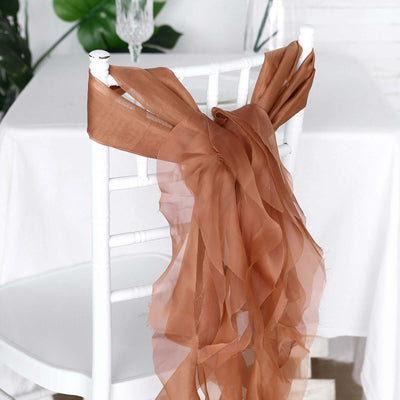 Brown chiffon chair sash tied on a white chair in a decorated setting.