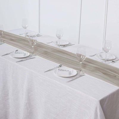 Elegant table setting with a neutral runner, plates, and glassware arranged for dining.