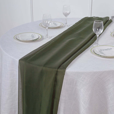 Olive green table runner on a white tablecloth with plates and glasses.