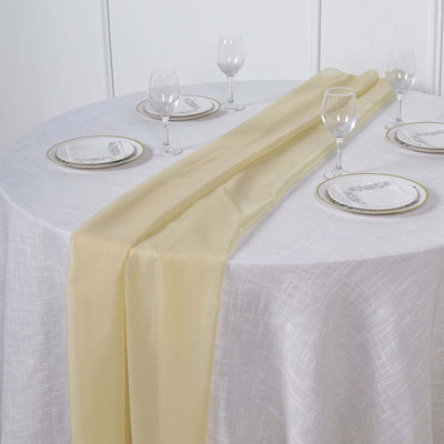 Yellow table runner on a white table with elegant glassware and plates.