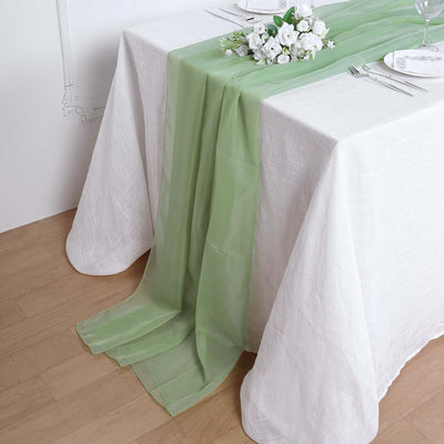Green table runner draped over a white tablecloth with floral decor.