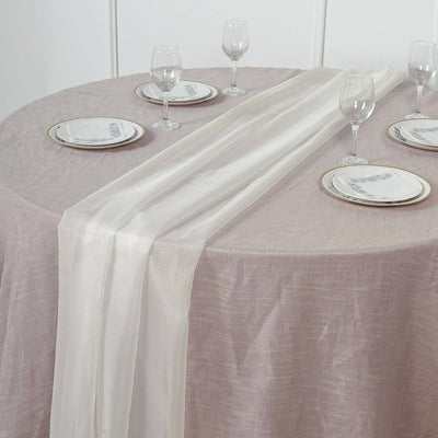 Elegant table setting with sheer table runner and glassware on a textured tablecloth.
