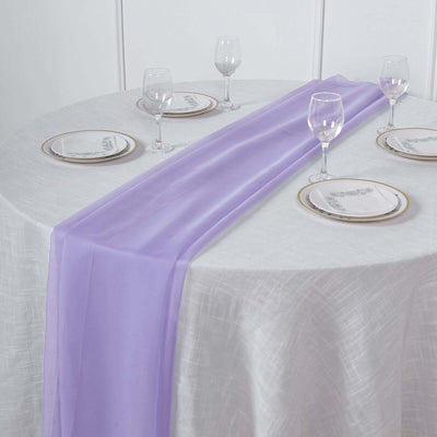 Purple table runner on a round table set with plates and glasses.