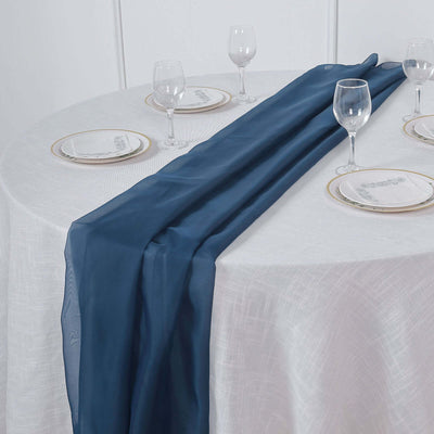 Navy blue table runner on a white table with elegant dinnerware