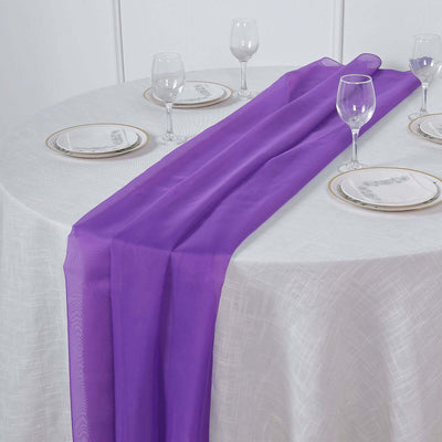 Purple table runner on a white table setting with plates and glasses.
