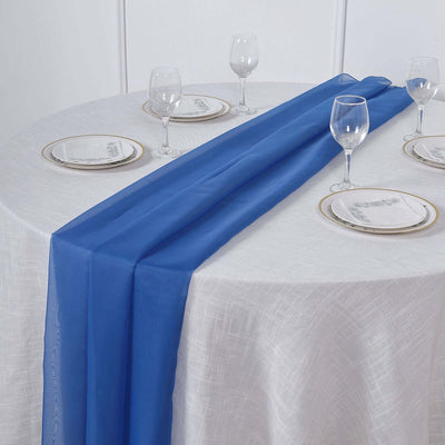 Blue table runner on an elegantly set dining table with glassware and plates.