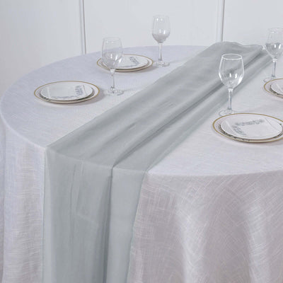 Gray table runner on a white table with elegant glassware and plates.