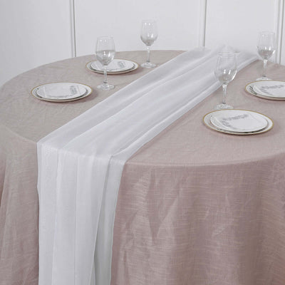 Elegant table setting with white and beige table linens and glassware.