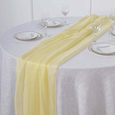 Yellow sheer table runner on a white tablecloth with elegant dinnerware.