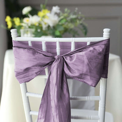 Purple chair sash elegantly tied on a white chair, set against a blurred floral backdrop.