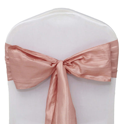 Rose satin chair sash tied in a bow on a white chair.