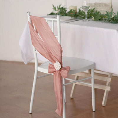 Blush pink chair sash with flower decoration at a decorated dining table.