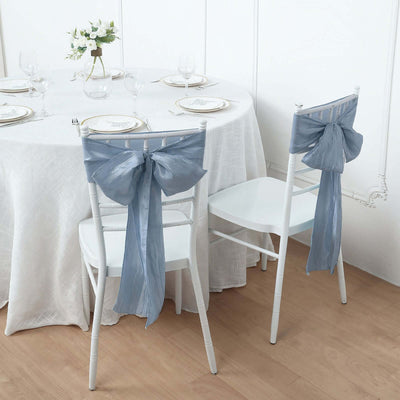 Elegant blue chair sashes on white chairs at a beautifully set dining table.