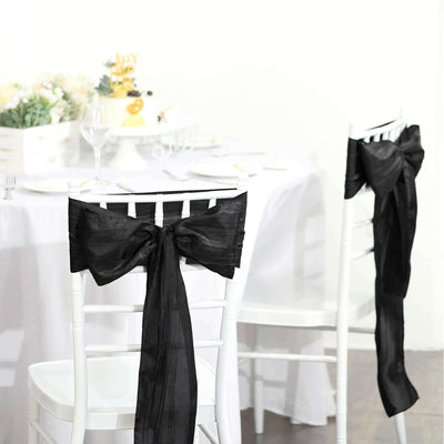 Black chair sashes tied in bows for elegant event decoration.