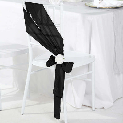 Black chair sash with white rose decoration on a white chair.
