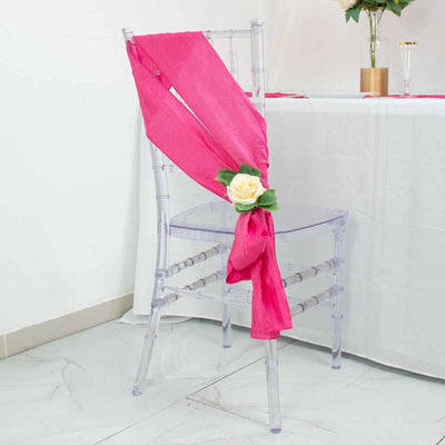 Transparent chair with pink sash and floral decoration on a white backdrop.
