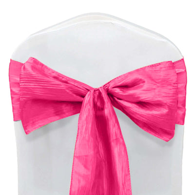 Pink satin chair sash tied in a bow on a white chair.