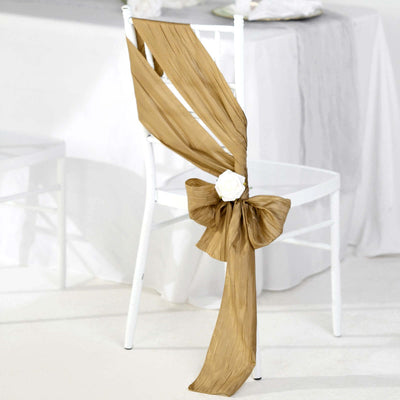 Gold chair sash with bow and flower decoration on a white chair.