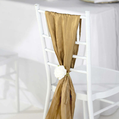 Gold chair sash with white rose decoration on a white chair.