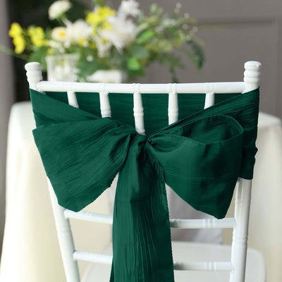 Green satin chair sash tied in a bow on a white chiavari chair.