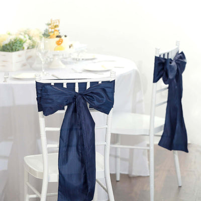Navy blue chair sashes tied in bows for elegant event decor.