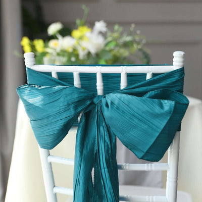 Teal satin chair sash tied in a bow on a white chiavari chair.
