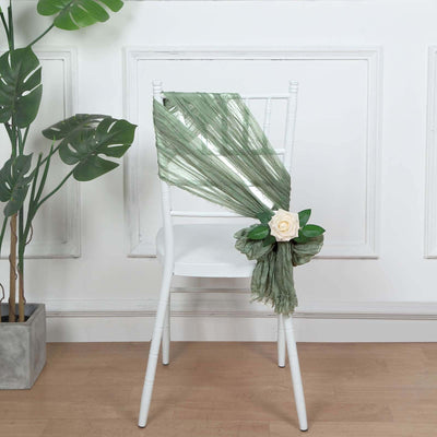 Green chiffon chair sash with a white rose and leaves on a white chair.