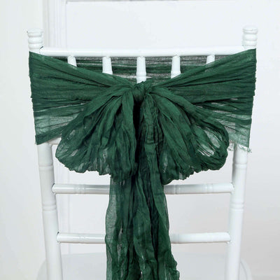 Green scarf tied on a white chair back for elegant decor.